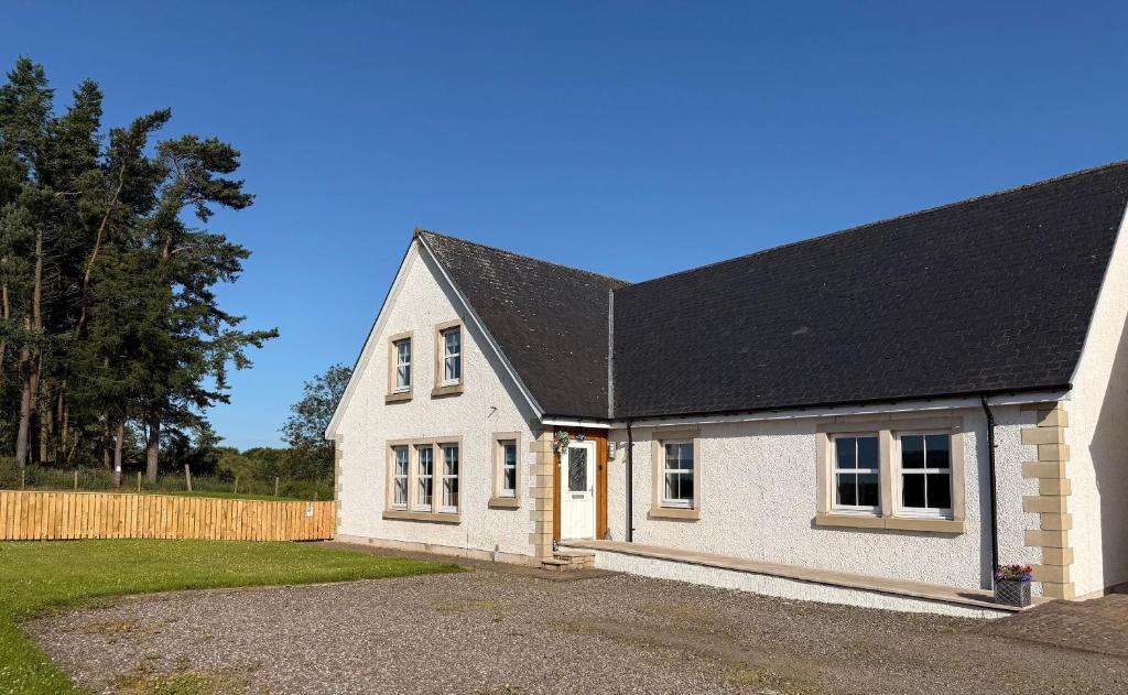 a white brick house with a black roof at Gellyburn Cottage in Kinross