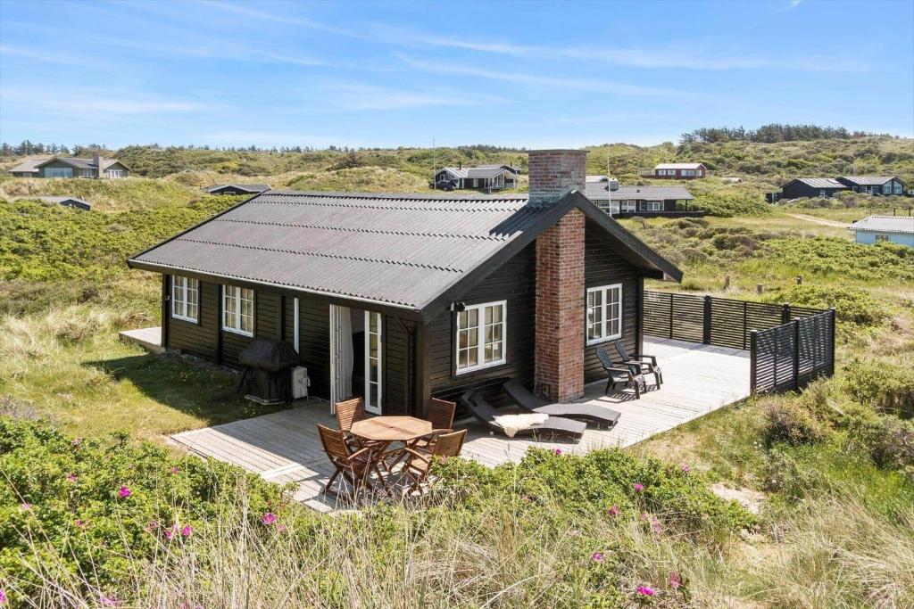 a small house on a hill with a deck at LN1883-Hjorring-Revlingrenden-13 in Hjørring