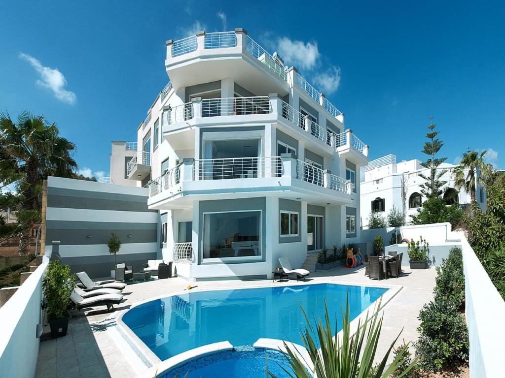 een groot wit gebouw met een zwembad ervoor bij Villa belvedere in St Julian's