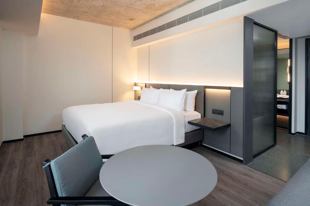 A modern guest room with a large bed, round table, and partially screened entry area.