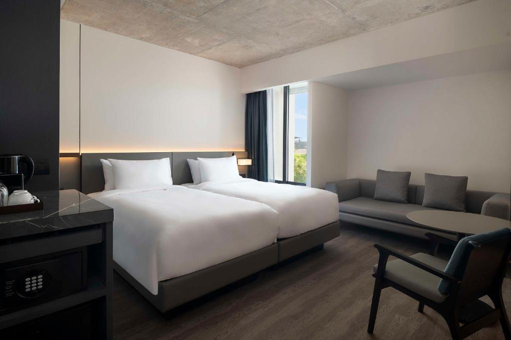 A twin room with two separate beds, a sofa and a small lounge chair beside the window.