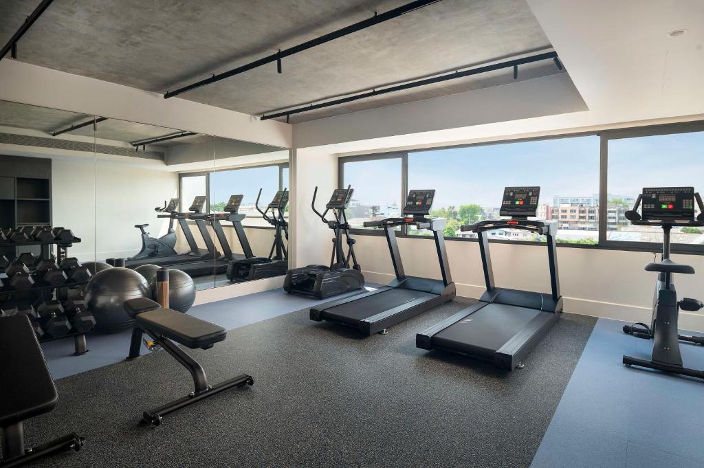 A bright fitness room with treadmills, an elliptical, free weights and large windows.