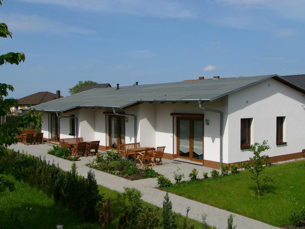 ein weißes Haus mit Tischen und Stühlen davor in der Unterkunft Ferienwohnanlage Jan in Neuendorf