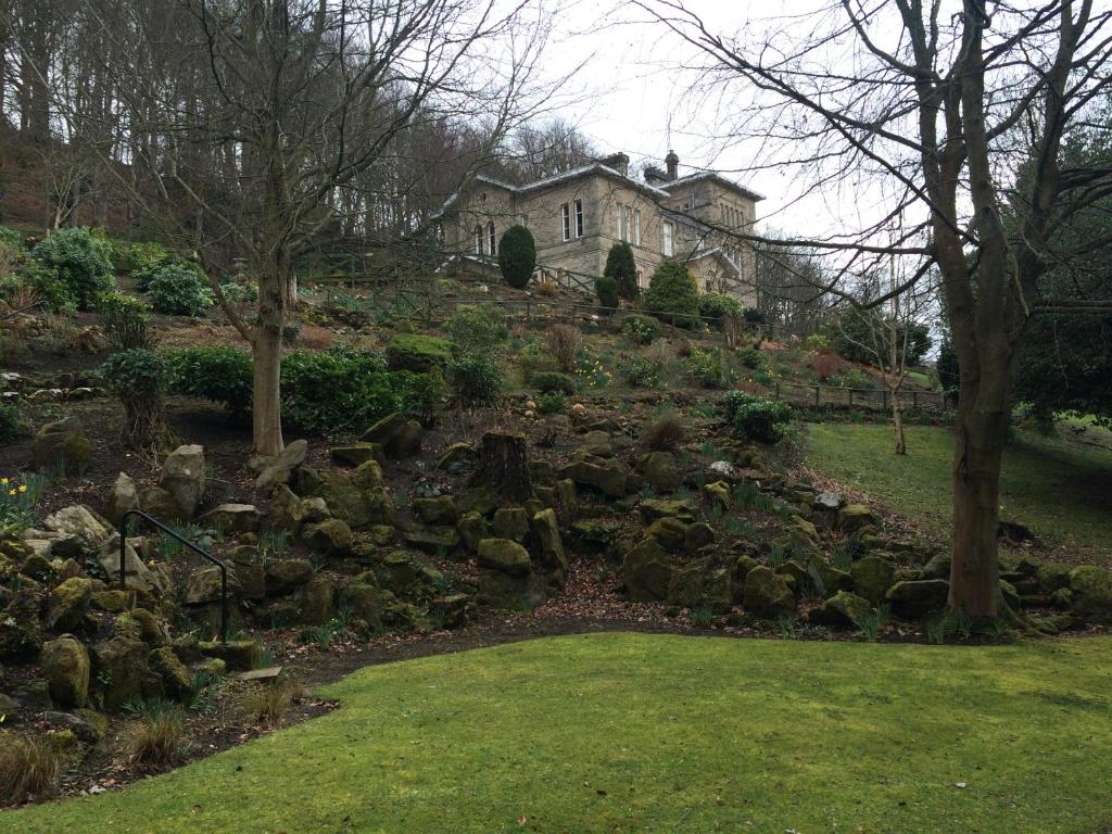 a garden with rocks and a house in the background at Mansfield House Hotel in Hawick