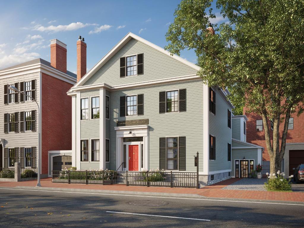 a white house with a red door on a street at Cambridge Common House in Cambridge