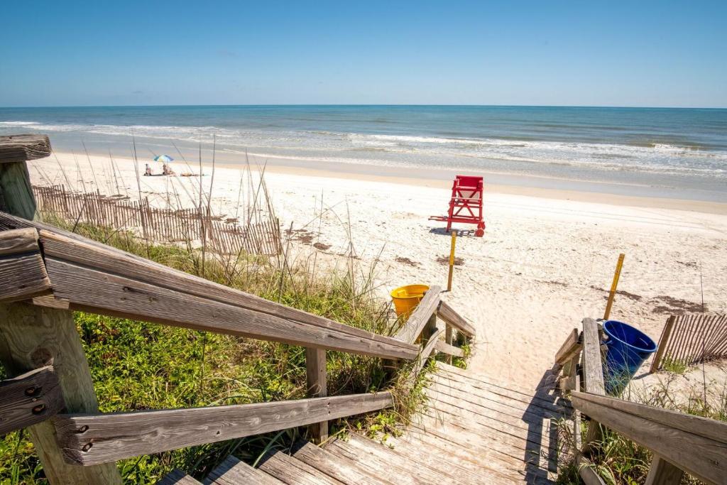 a wooden staircase leading to a beach with a red chair at Ocean Walk 3-404 in Bottle Island