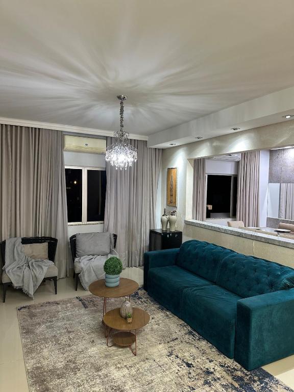 a living room with a blue couch and a table at Apartamento localizado no centro da cidade in Primavera do Leste