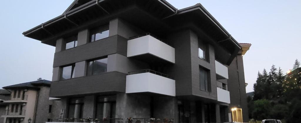 Un edificio blanco y negro con gente delante de él. en Green apartment Velingrad, en Velingrad