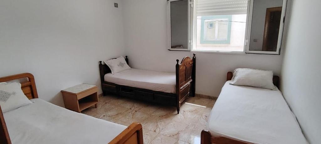 a room with two beds and a chair and a window at chatt mariem sousse in Chott Meriem