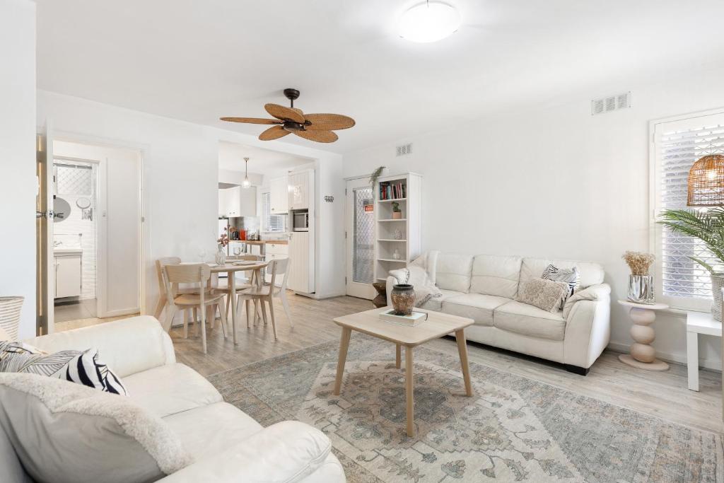 Una sala de estar con muebles blancos y un ventilador de techo. en Rockingham Beach Breeze 2br Retreat, en Rockingham