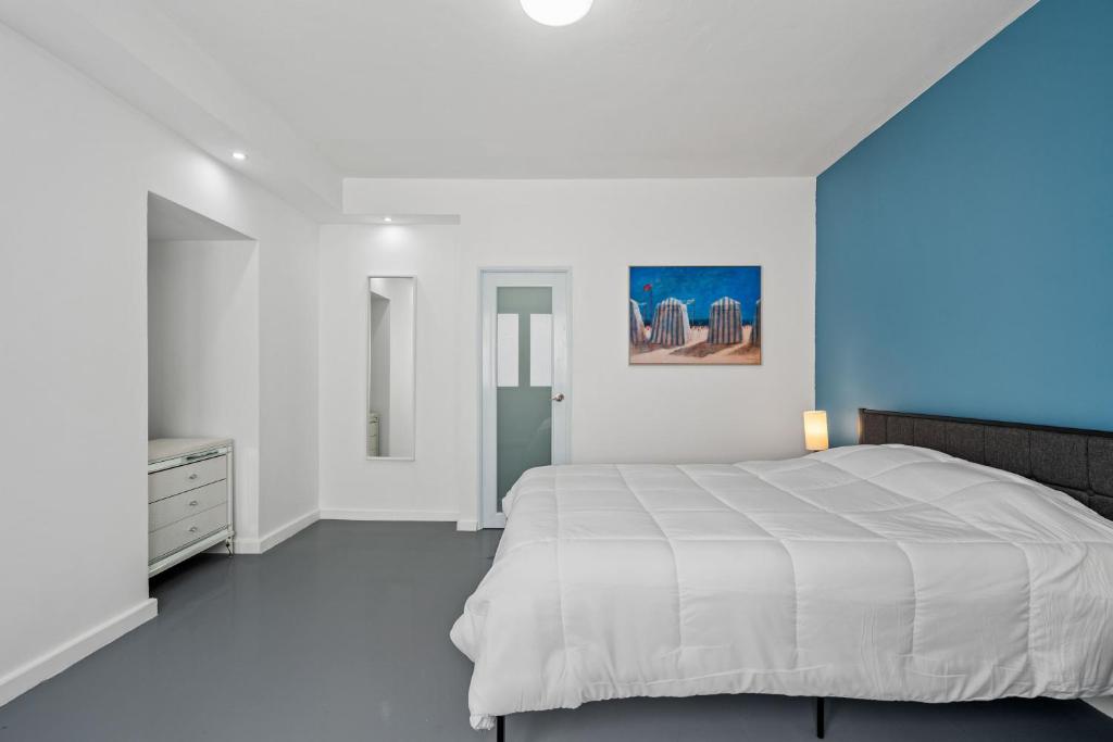 a bedroom with a white bed and a blue wall at 65 Condado by Otium in San Juan