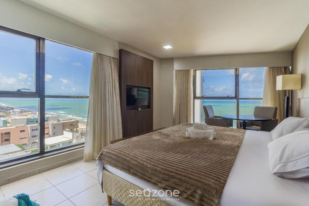 a bedroom with a large bed with a view of the ocean at Estúdio Vista Mar em Recife BCI1603 in Recife