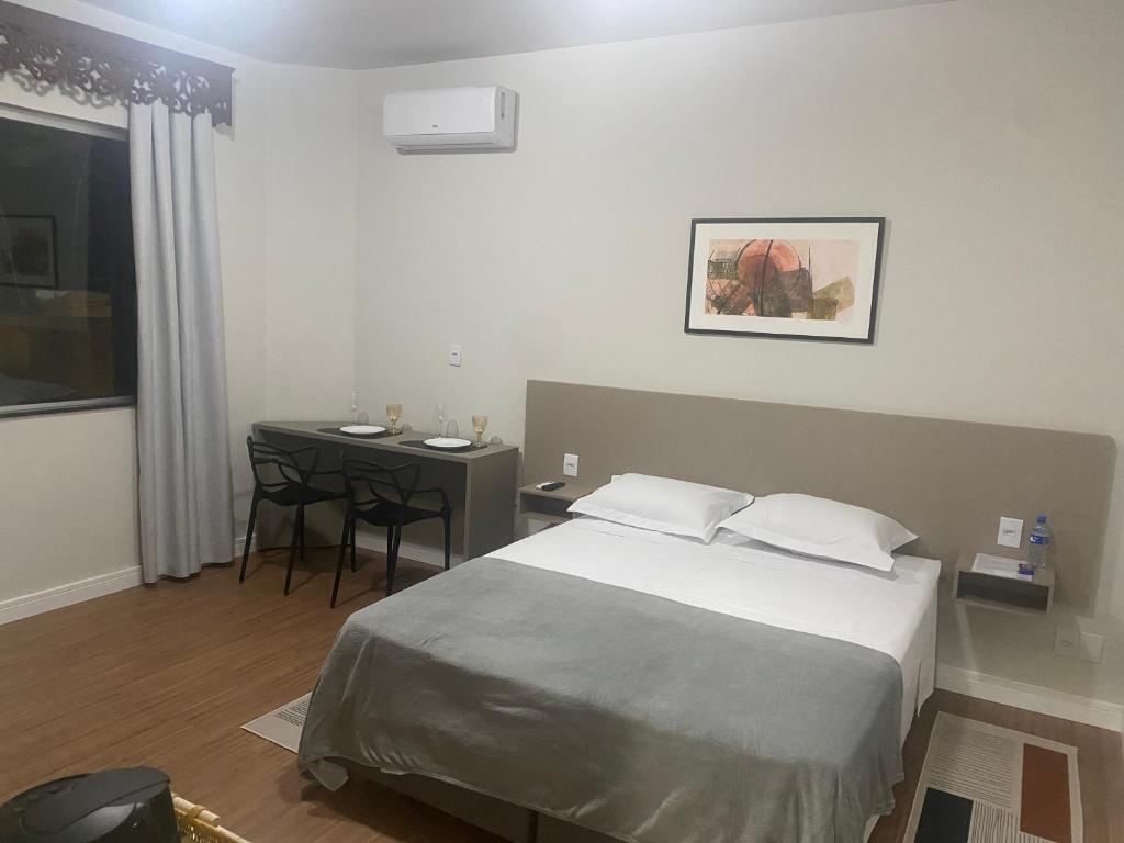 a bedroom with a bed and a desk and a table at Loft Design in Curvelo