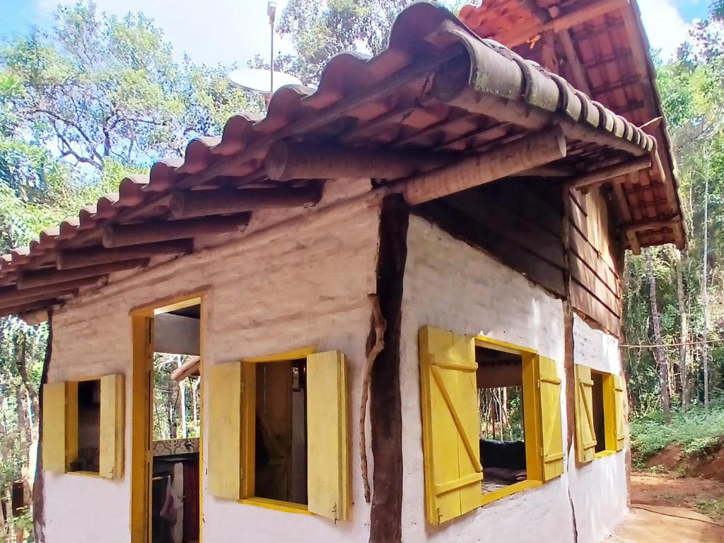 een klein huisje met gele ramen en een dak bij Canto da Águia in Ouro Preto