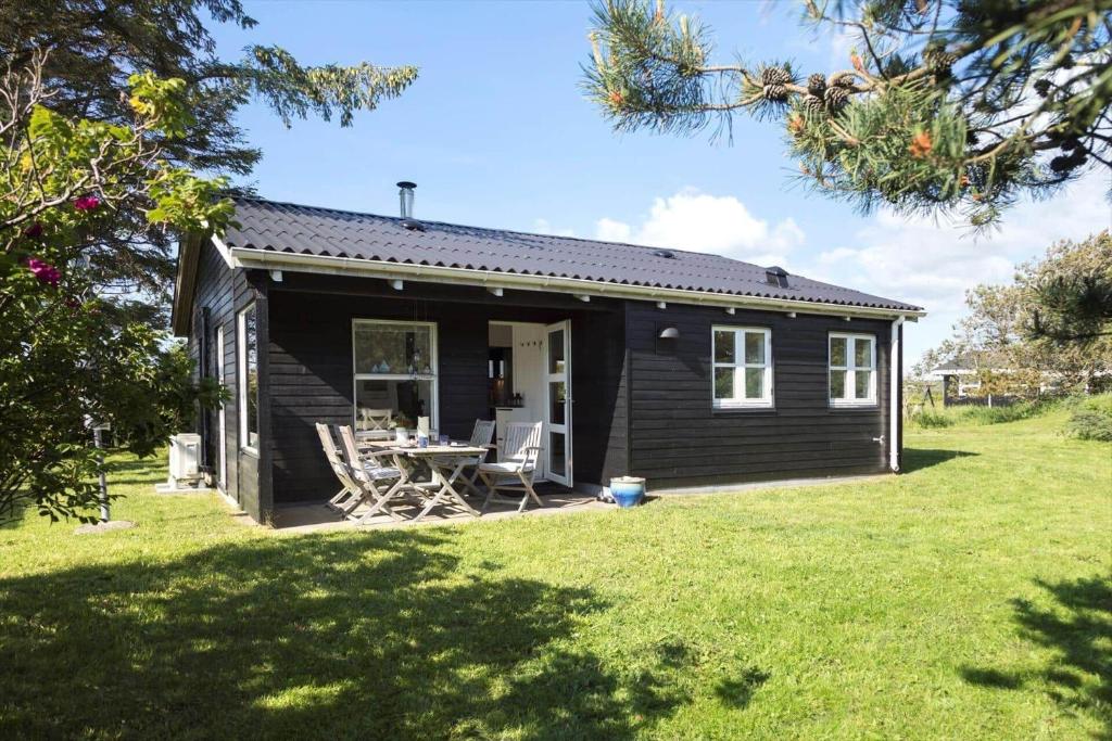 a black house with a table and chairs in a yard at LN1987-Hjorring-Havbruset-6 in Hjørring
