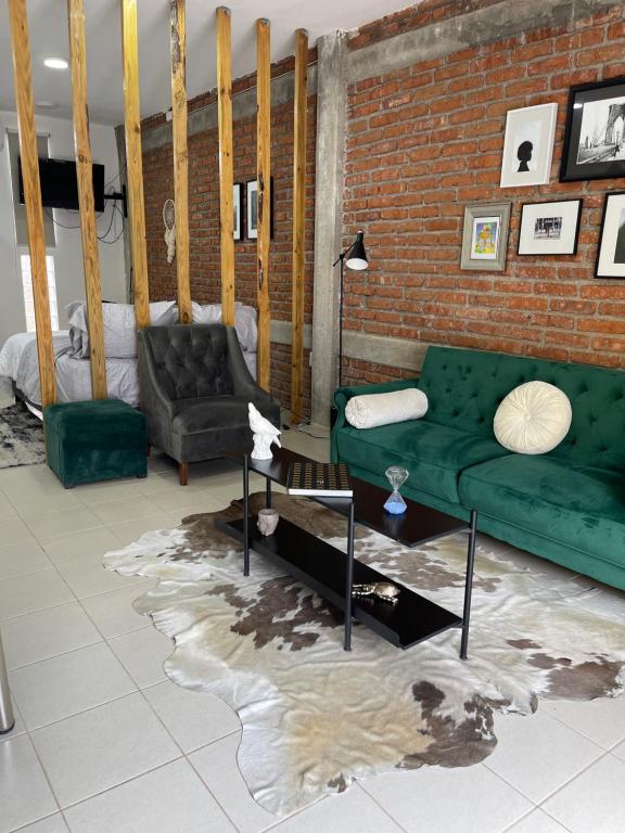 a living room with a green couch and a brick wall at Loft cerca de todo con cochera in León