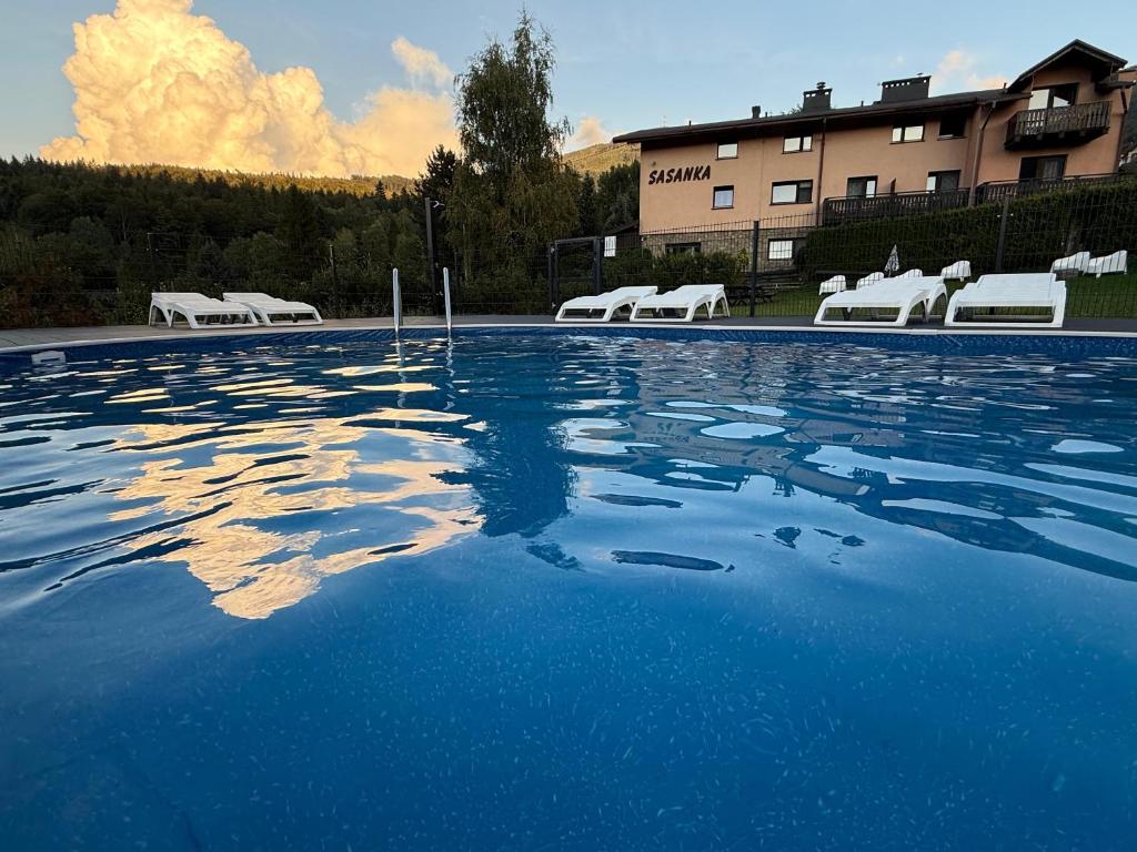 a large swimming pool with chairs and a building at Sasanka przy Gondoli podgrzewany basen w cenie pobytu in Szczyrk