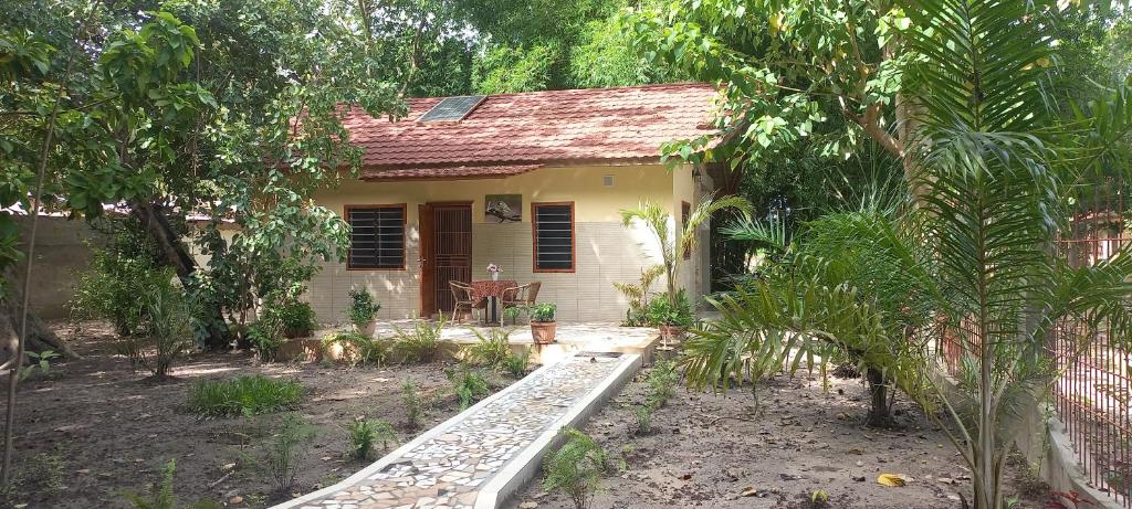 a small yellow house with a garden in front of it at Busy Bee Nature Residence in Mariama Kunda