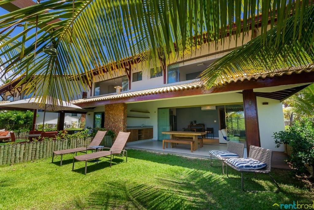 a house with a patio with chairs and a table at Ykutiba Imbassaí - Bangalô - J01 in Imbassai