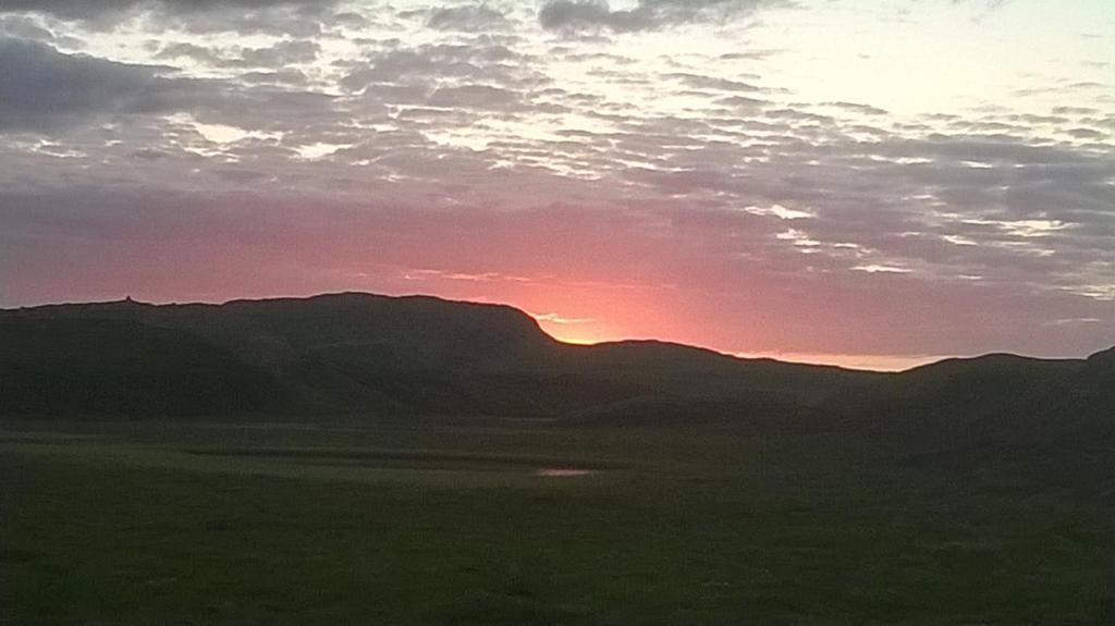 um pôr-do-sol sobre um campo com montanhas ao fundo em Setberg em Egilsstadir