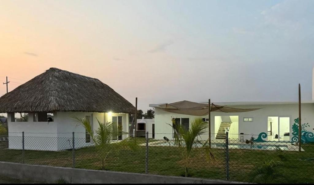 a white house with a thatch roof at Almirante del Mar in El Naranjo