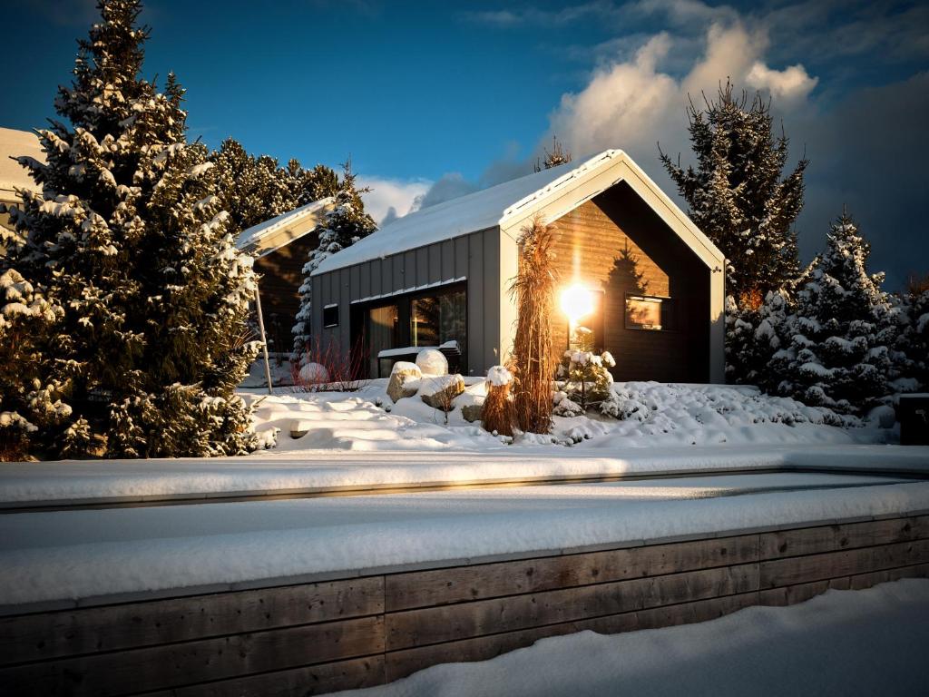 a cabin in the snow with the light on at SKARPA resort in Ustronie Morskie