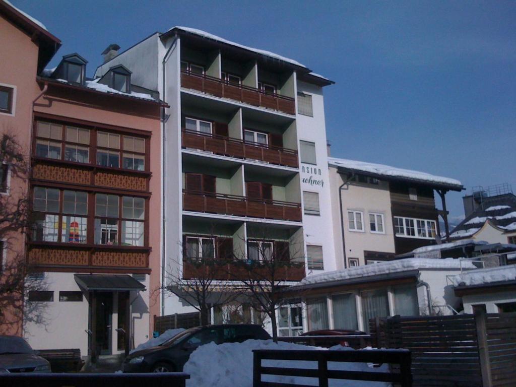 un edificio alto con nieve delante en Pension Buchner, en Zell am See
