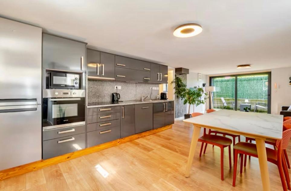 a kitchen with stainless steel appliances and a wooden table at Côté Jardin, Entre lac et montagne in Publier