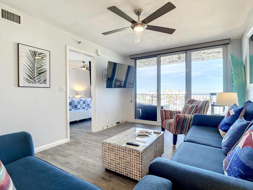un salon avec des canapés bleus et un balcon dans l'établissement Beachfront Condo - OceanView, Pool & Steps to Flagler Ave, à Chicken Island