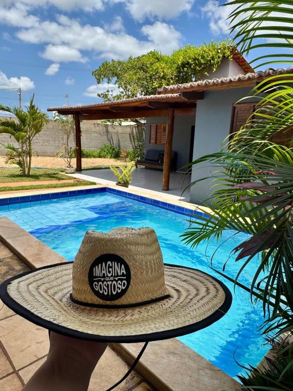 a straw hat sitting on a table next to a swimming pool at Recanto Celestino 3 in São Miguel do Gostoso
