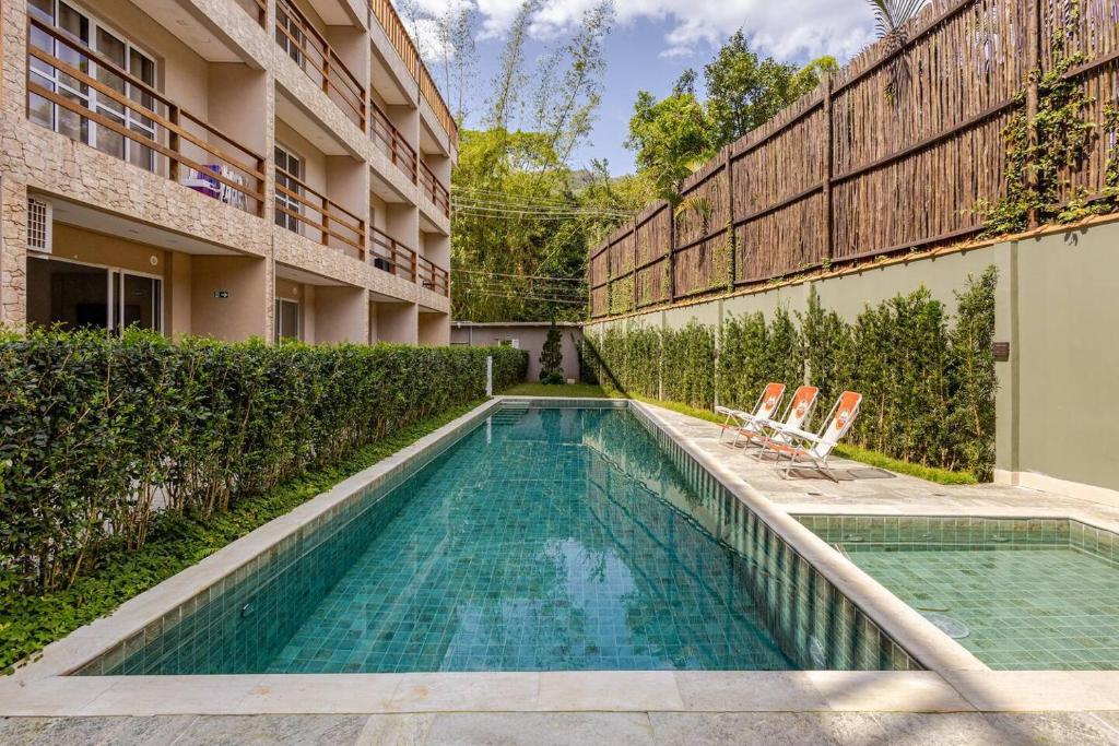 a swimming pool with two chairs next to a building at Condomínio Eclipse Village, Praia de Juquehy in São Sebastião