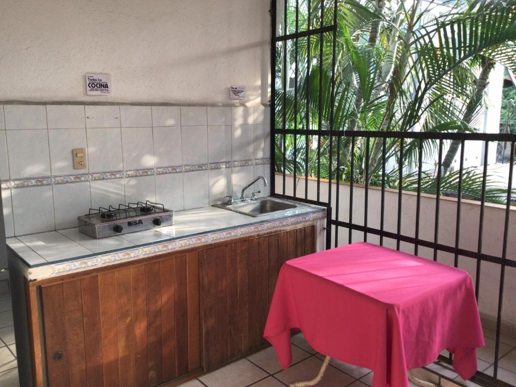 a kitchen with a sink and a table with a pink stool at Hotel Villa Tulipanes in Zihuatanejo