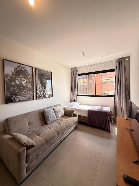 una sala de estar con un sofá y una cama en LK Santa Efigênia 2, en Belo Horizonte