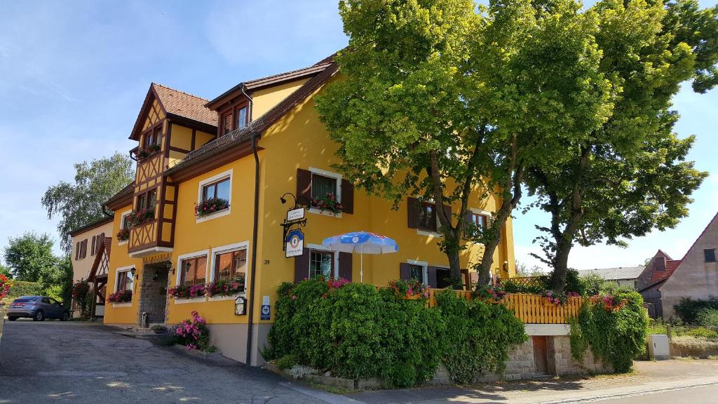 een geel huis met een paraplu op een straat bij Hotel Gasthof zum Schwan in Steinsfeld