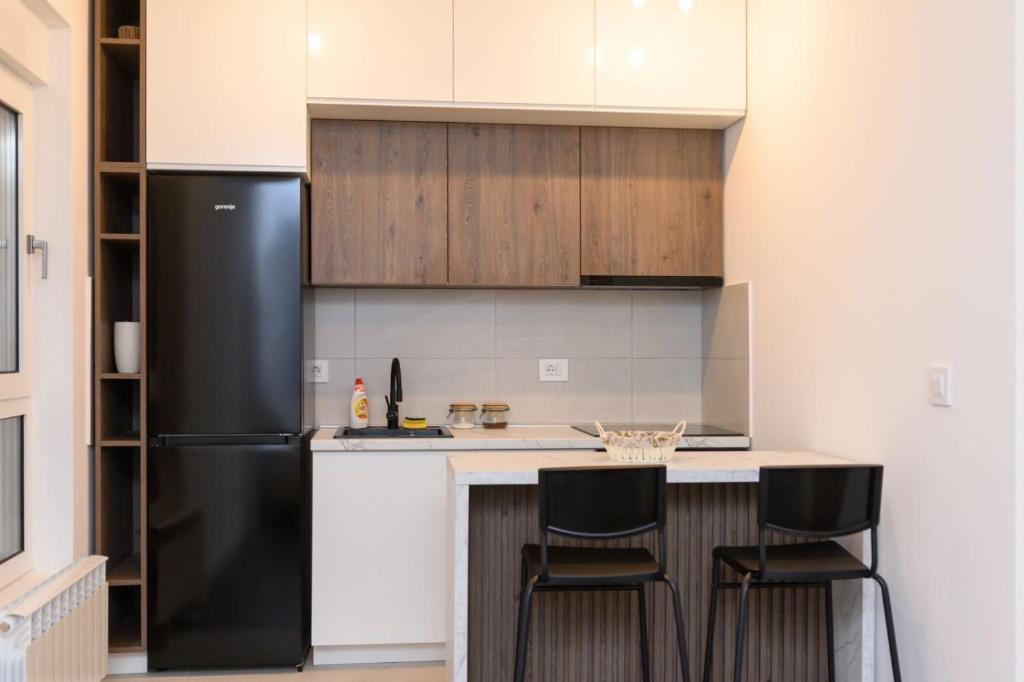 a kitchen with a black refrigerator and two bar stools at Tesla Apartments 1 in Kragujevac