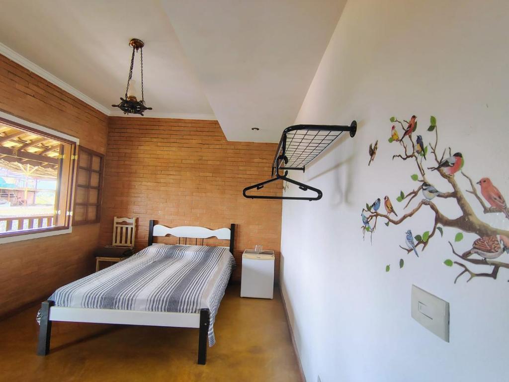 - une chambre avec un lit et un arbre sur le mur dans l'établissement Suites da Cla - Suite 1, à Lima Duarte