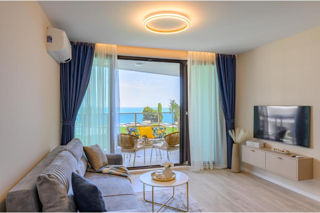 a living room with a couch and a television at Luxury Sea View Appartment with Beach Access - Parking & Heated Pool in Varna City