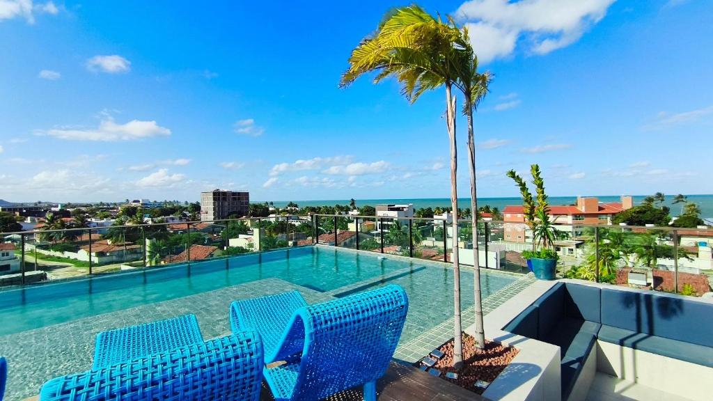 a swimming pool with blue chairs and a palm tree at Makani Beach Campas - Praia de Tamandaré in Tamandaré