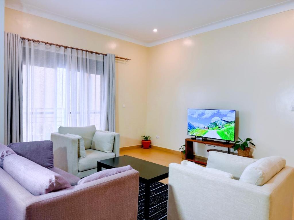 a living room with two couches and a flat screen tv at 3-bedroom Spacious Munyonyo Home in Kampala