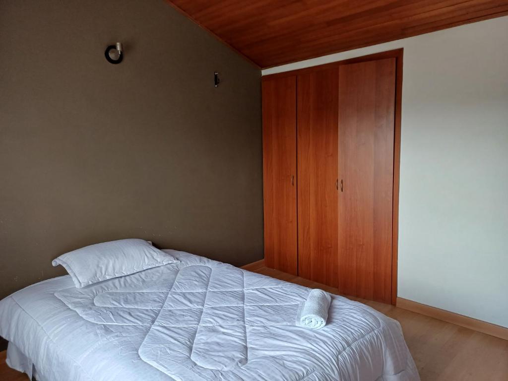 a bedroom with a bed and a wooden cabinet at CASA BOUTIQUE Villa del Prado in Bogotá