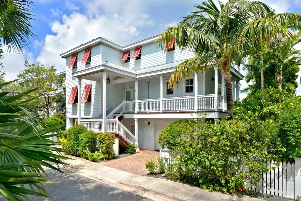 a white house with red windows and a palm tree at Mother Ocean in Key West