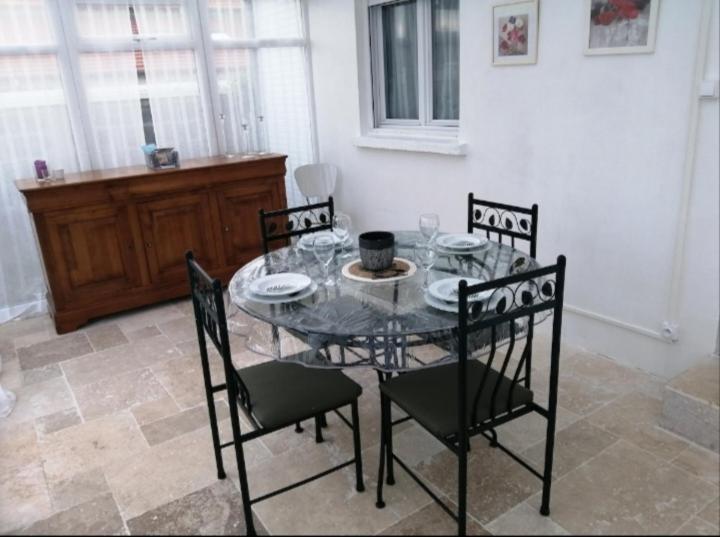 a dining room table with four chairs and a glass table at Charmante petite maison de ville à 20 minutes de la mer in Giberville