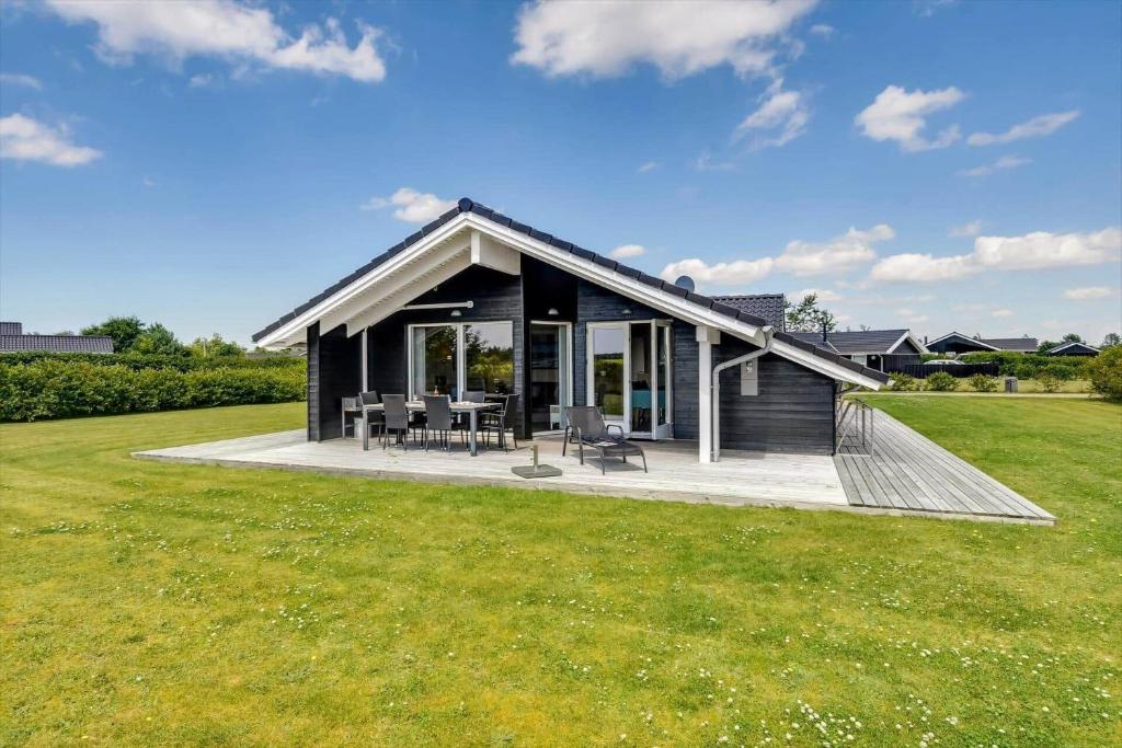 una pequeña casa negra con patio y césped en C11329-Tarm-Sortbaervej-16, en Tarm