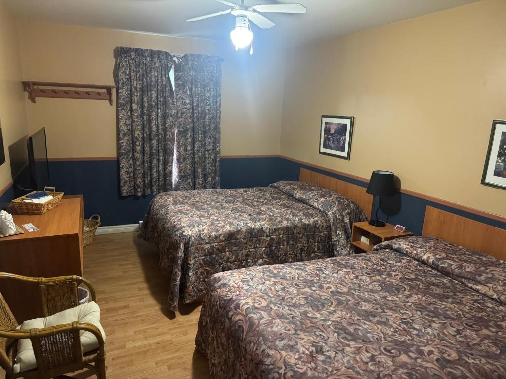 a hotel room with two beds and a ceiling fan at Auberg & Motel Moka Creme in Lévis
