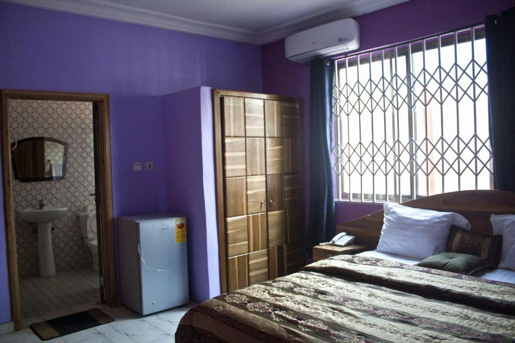 1 dormitorio con paredes moradas, 1 cama y ventana en Rasra building, 