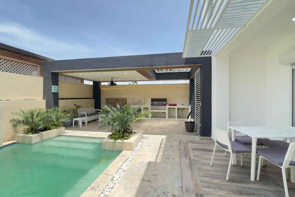 une terrasse avec une piscine, une table et des chaises dans l'établissement Elegante Casa Estrella Marina 117 Pool BBQ, à La Romana