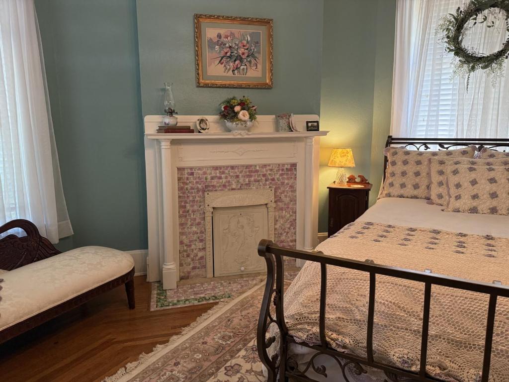 a bedroom with a fireplace with a bed and a chair at The Redbud Room at The Judges Chambers in Guthrie