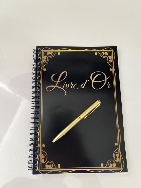 a spiral notebook with a clock and a pen on it at L echappée d Opale - Jardin Privé et à 5 min de Ste Cécile Plage in Camiers