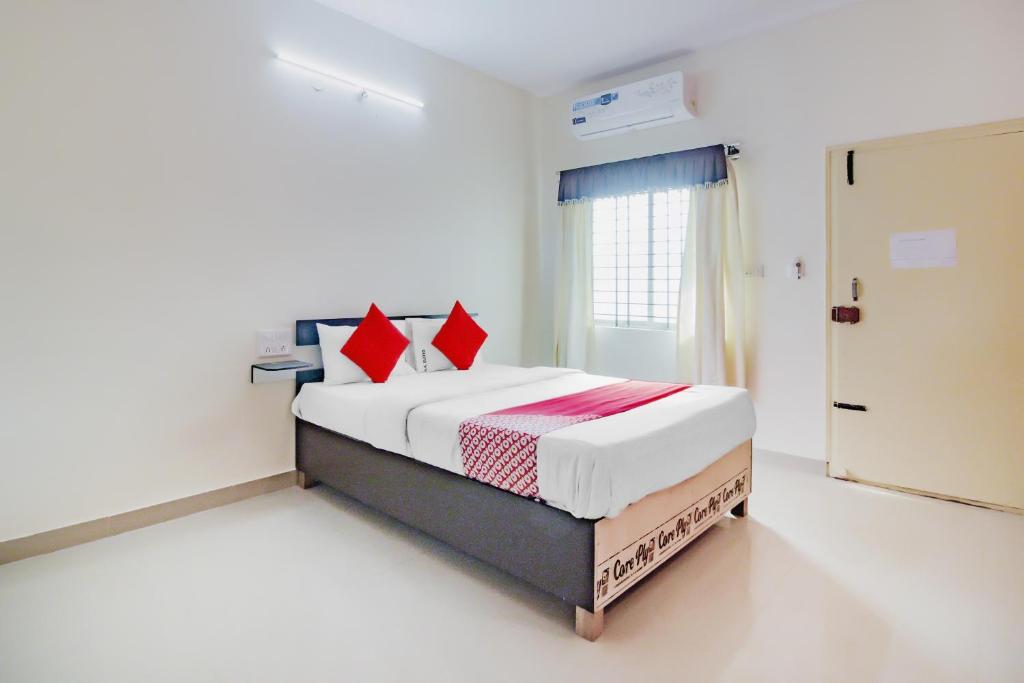JālahalliにあるHotel O P N K Suitesのベッドルーム1室(大型ベッド1台、赤い枕付)