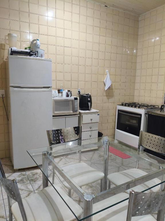 a kitchen with a glass table and a refrigerator at CASA Aconchegante MASSUDA in São Paulo
